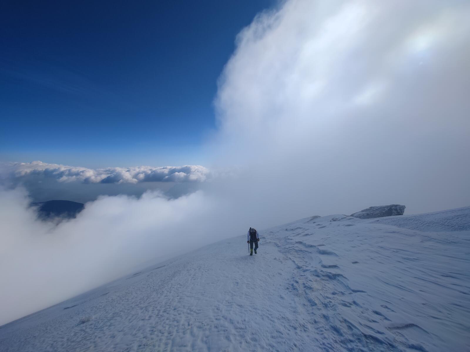 A climber breaking through the cloud layer, with a sea of clouds below.